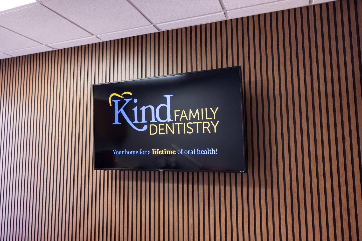img slider photo 1 new Kind Family Dentistry illuminated sign mounted on wooden slat wall in dental office.